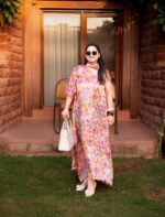 “Floral kaftan dress styled with white statement flats, sunglasses, and embroidered tote bag for an elevated vacation look.